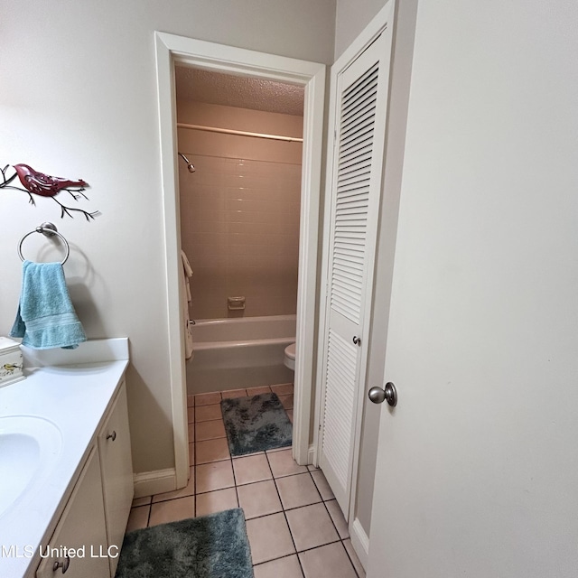 full bathroom featuring a textured ceiling, toilet, vanity, tiled shower / bath combo, and tile patterned floors