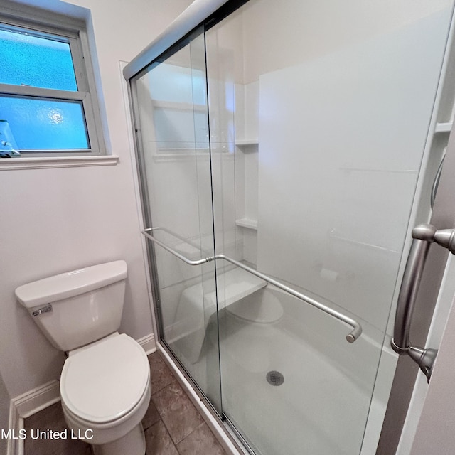 bathroom featuring a shower with shower door, toilet, and tile patterned flooring