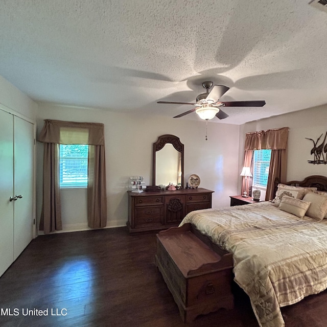 bedroom with multiple windows, a textured ceiling, dark wood-type flooring, and ceiling fan