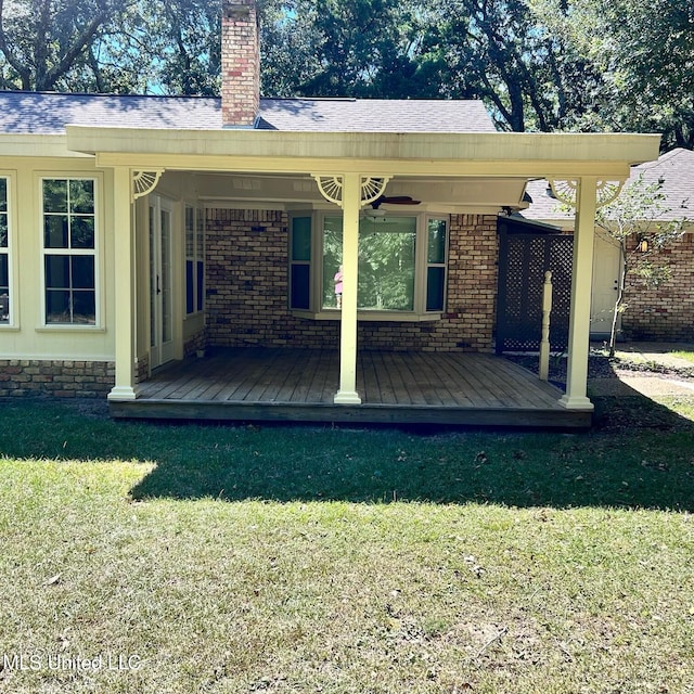 back of property featuring a wooden deck and a yard