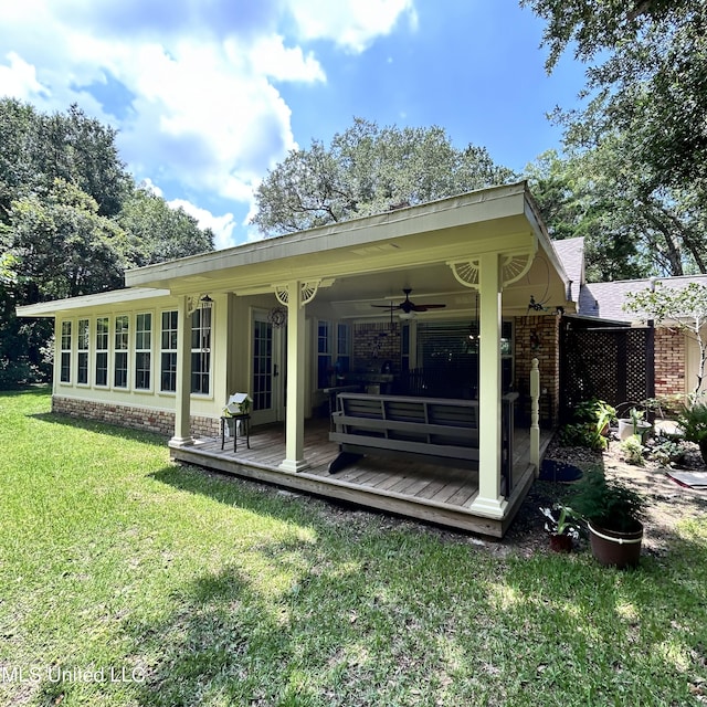 back of house featuring a yard, ceiling fan, and a deck