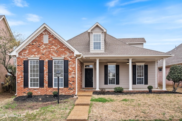 traditional home featuring a ceiling fan, covered porch, brick siding, and a shingled roof