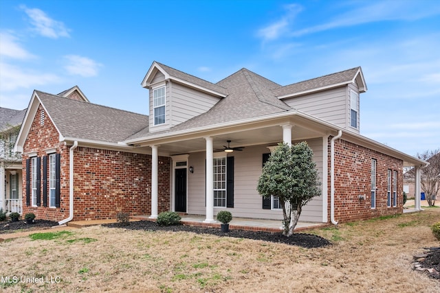 view of front of property with brick siding, ceiling fan, a front lawn, and roof with shingles