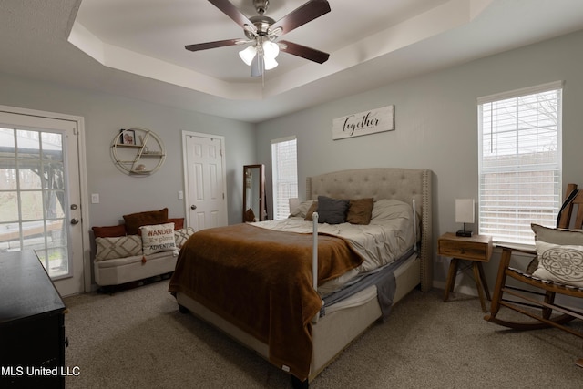 bedroom with multiple windows, access to exterior, light colored carpet, and a raised ceiling