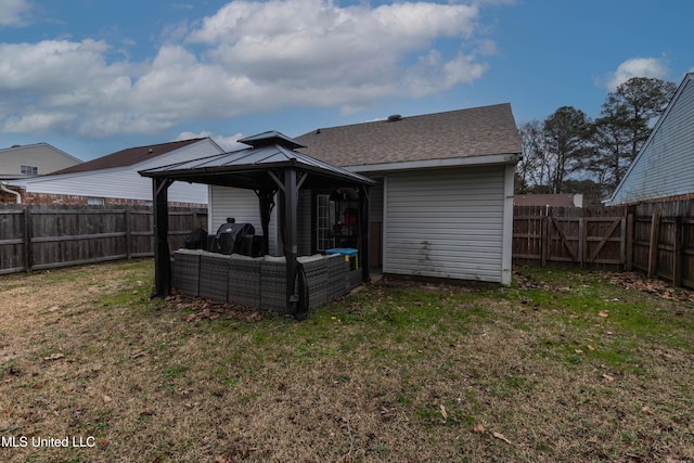 back of property featuring a gazebo and a lawn