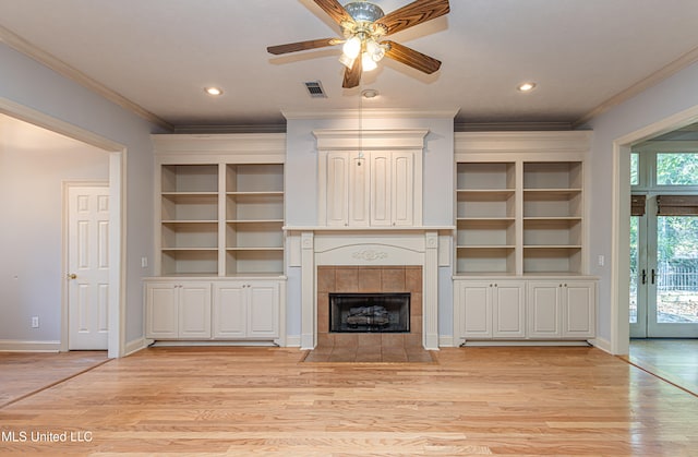 unfurnished living room with light wood-type flooring, a tiled fireplace, and crown molding