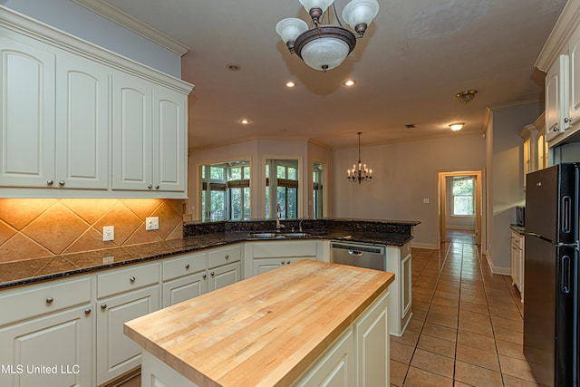 kitchen with black fridge, kitchen peninsula, a healthy amount of sunlight, a kitchen island, and wood counters