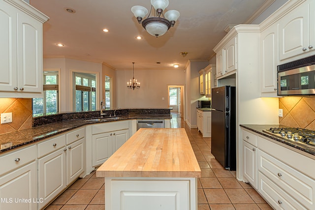 kitchen with white cabinets, appliances with stainless steel finishes, butcher block countertops, and a kitchen island