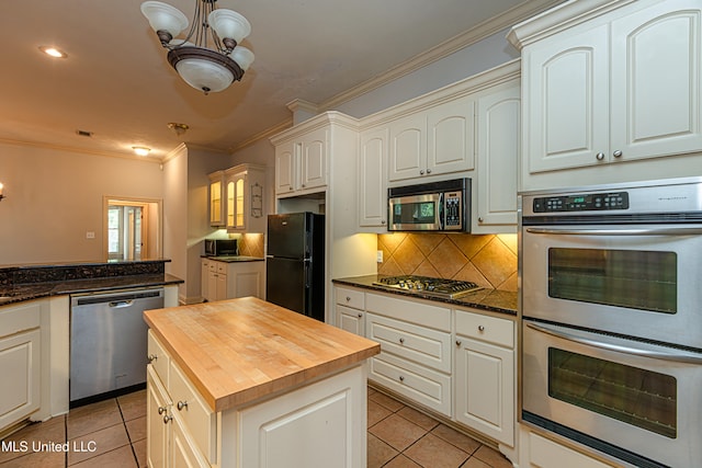 kitchen featuring ornamental molding, stainless steel appliances, butcher block counters, and light tile patterned floors