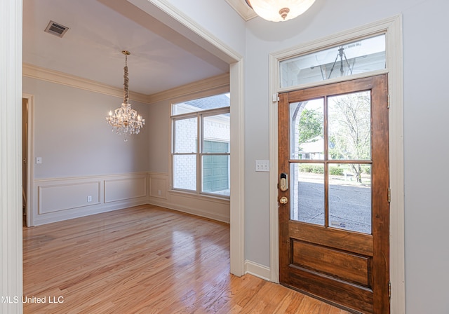 entrance foyer with light hardwood / wood-style flooring, a notable chandelier, and crown molding