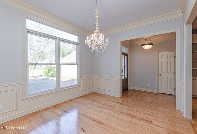 unfurnished dining area featuring an inviting chandelier, light hardwood / wood-style flooring, and ornamental molding