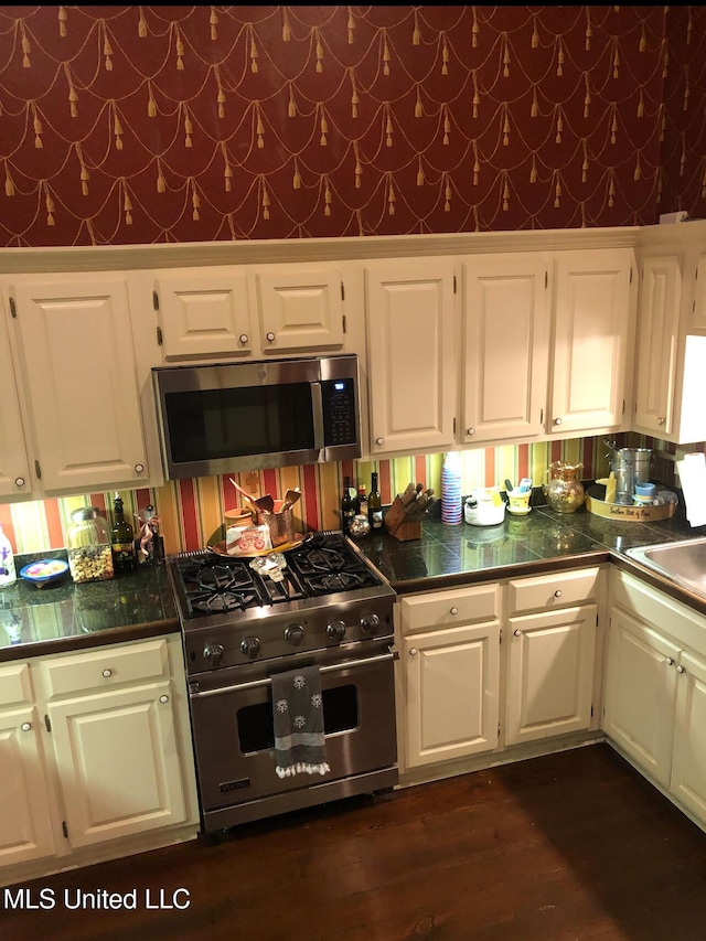 500 Franklin St, Natchez, MS 39120 - kitchen featuring appliances with stainless steel finishes, white cabinets, wallpapered walls, dark wood finished floors, and tile countertops