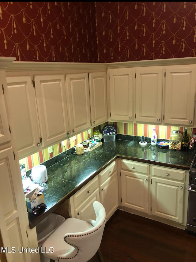 500 Franklin St, Natchez, MS 39120 - kitchen with wallpapered walls, white cabinetry, dark wood finished floors, and tile countertops