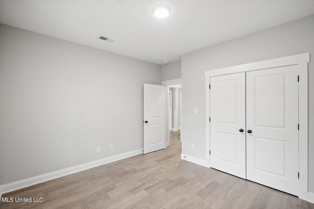 unfurnished bedroom with light hardwood / wood-style flooring and a closet