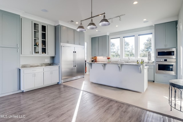 125 Miramar Ave, Biloxi, MS 39530 - kitchen featuring a breakfast bar area, light stone counters, built in appliances, hanging light fixtures, and light hardwood / wood-style floors