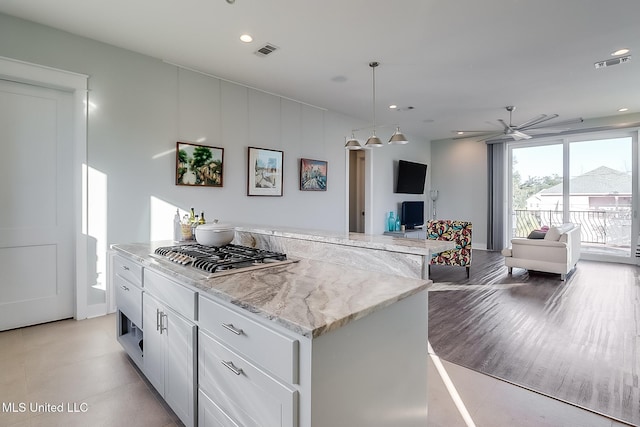 125 Miramar Ave, Biloxi, MS 39530 - kitchen with stainless steel gas stovetop, white cabinetry, hanging light fixtures, a center island, and light stone countertops