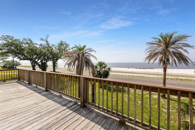 wooden deck with a water view, a yard, and a beach view