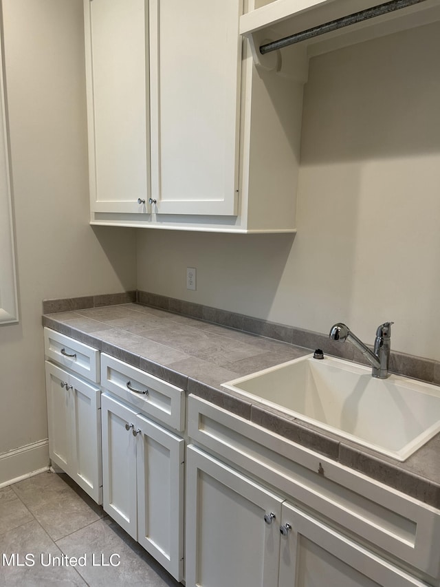 kitchen featuring sink, white cabinetry, and light tile patterned floors