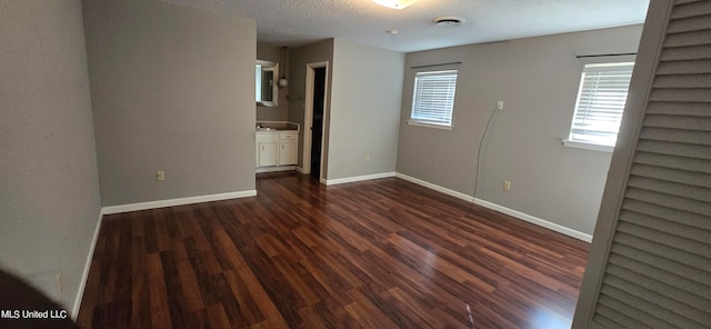 spare room with a textured ceiling and dark hardwood / wood-style flooring