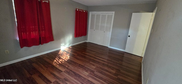 unfurnished bedroom with a closet and dark hardwood / wood-style floors