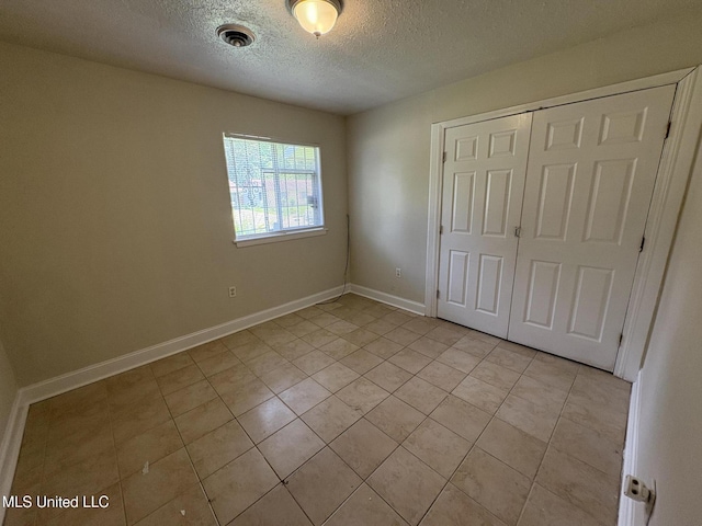 3435 Casa Grande Cir, Jackson, MS 39209 - unfurnished bedroom featuring a textured ceiling, light tile patterned flooring, a closet, and baseboards