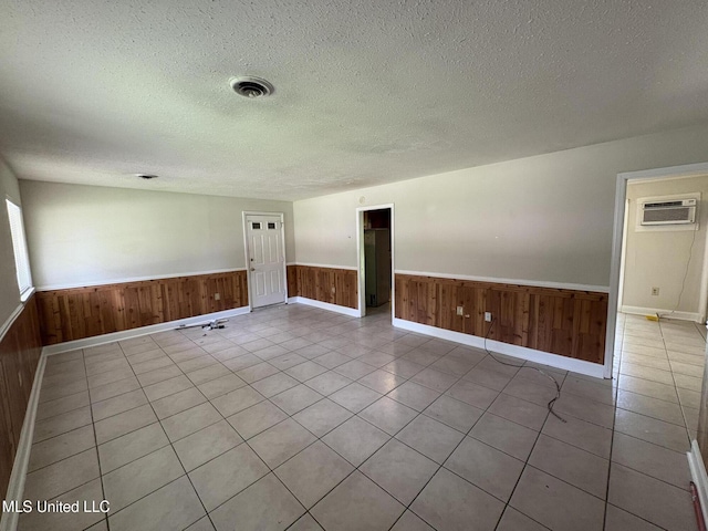 3435 Casa Grande Cir, Jackson, MS 39209 - tiled spare room featuring wainscoting, a textured ceiling, a wall unit AC, wood walls, and baseboards