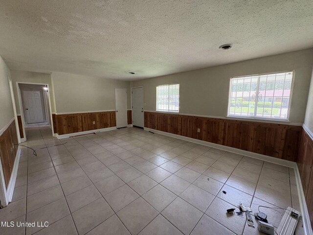 3435 Casa Grande Cir, Jackson, MS 39209 - unfurnished room featuring a wainscoted wall, wooden walls, a textured ceiling, and light tile patterned flooring