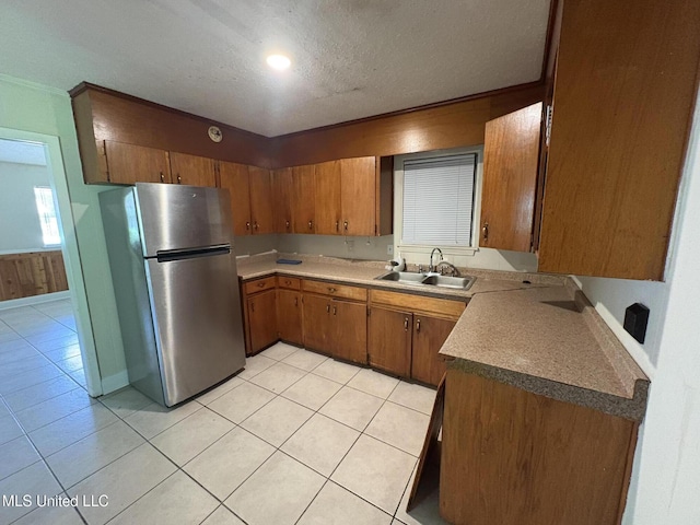 3435 Casa Grande Cir, Jackson, MS 39209 - kitchen with freestanding refrigerator, a sink, light tile patterned flooring, brown cabinets, and a textured ceiling