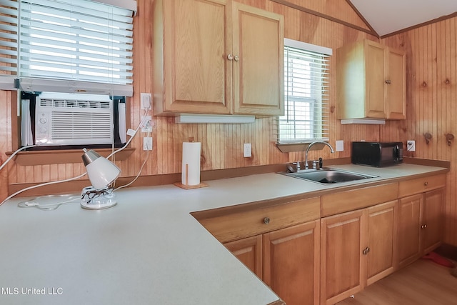 kitchen featuring wood walls, light brown cabinets, lofted ceiling, sink, and hardwood / wood-style flooring