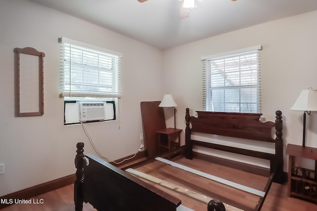 bedroom featuring hardwood / wood-style flooring, ceiling fan, cooling unit, and multiple windows