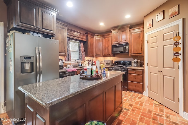 kitchen with dark stone countertops, sink, a kitchen island, and stainless steel appliances