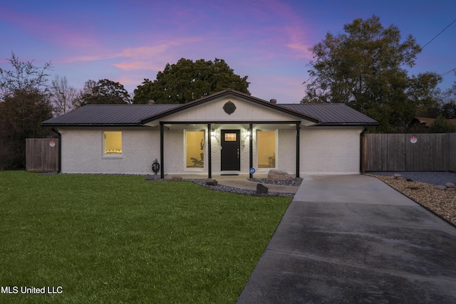 view of front of home with brick siding, metal roof, a front lawn, and fence