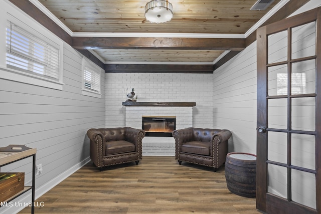 sitting room featuring visible vents, wood ceiling, wood finished floors, wood walls, and a brick fireplace