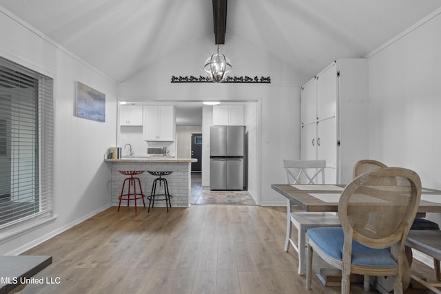 kitchen with a breakfast bar area, light wood-style flooring, a peninsula, white cabinetry, and freestanding refrigerator