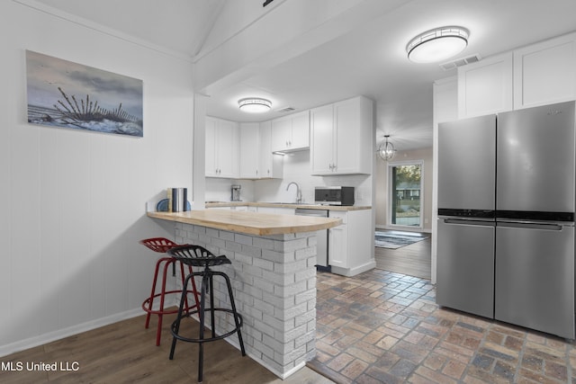 kitchen with brick floor, a breakfast bar area, visible vents, appliances with stainless steel finishes, and white cabinets