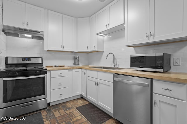 kitchen featuring stainless steel appliances, wooden counters, white cabinetry, a sink, and under cabinet range hood