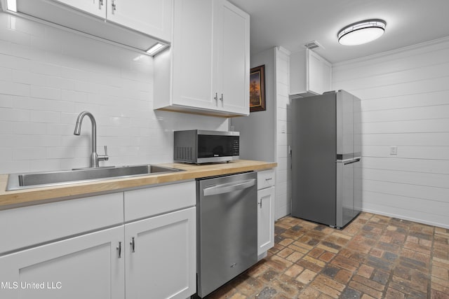 kitchen with visible vents, wood counters, brick floor, stainless steel appliances, and a sink