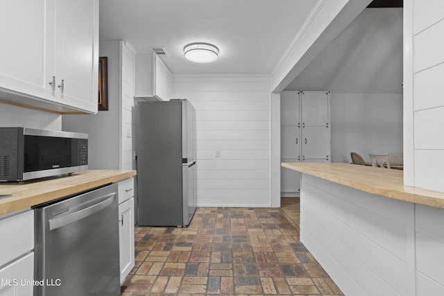 kitchen with visible vents, appliances with stainless steel finishes, brick floor, white cabinetry, and wooden counters