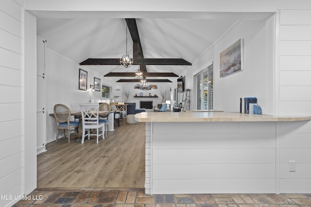 kitchen with vaulted ceiling with beams, brick floor, and open floor plan