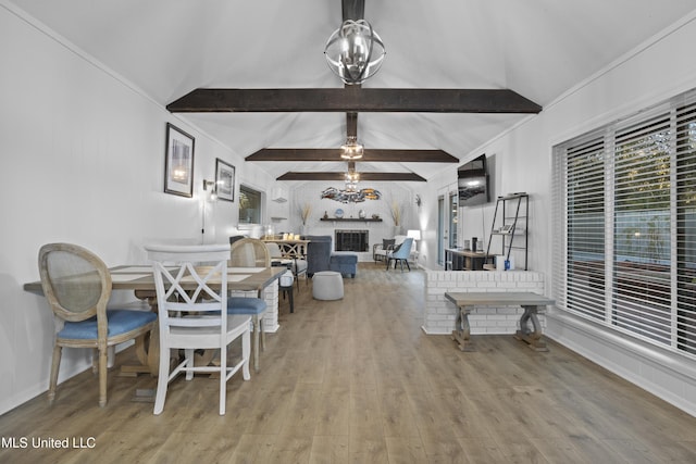 dining space with a chandelier, a healthy amount of sunlight, vaulted ceiling with beams, and wood finished floors