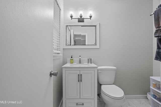 bathroom with marble finish floor, toilet, vanity, and baseboards