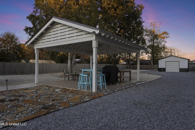 exterior space with a garage, a fenced backyard, grilling area, an outbuilding, and a gazebo