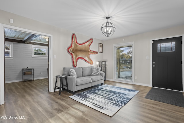 living room with baseboards, a notable chandelier, wood finished floors, and a healthy amount of sunlight