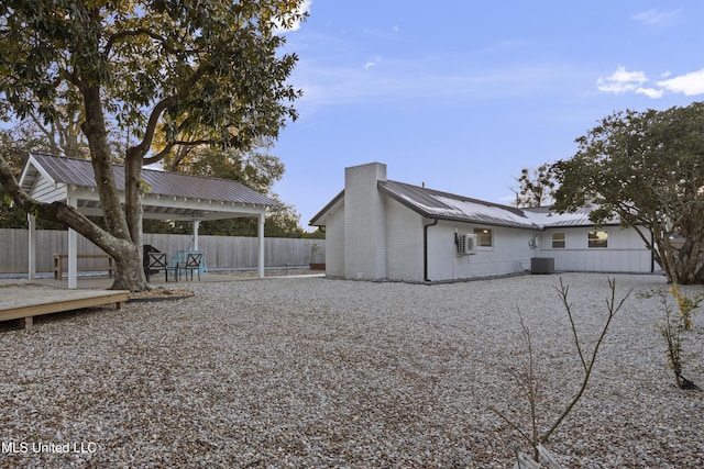 rear view of house with metal roof, a gazebo, a fenced backyard, and central air condition unit