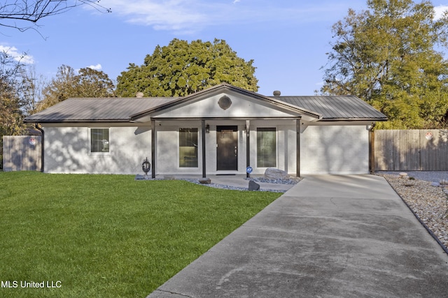 view of front facade with metal roof, brick siding, a front yard, and fence