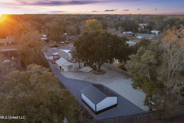 aerial view at dusk featuring a wooded view