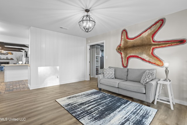 living area featuring baseboards, wood finished floors, visible vents, and an inviting chandelier