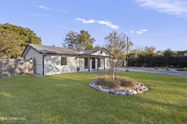 view of front of property with metal roof, a front lawn, and fence