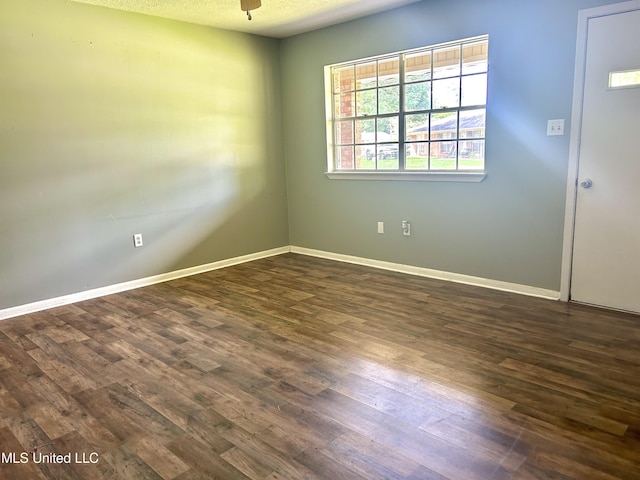 empty room with baseboards, dark wood finished floors, and ceiling fan