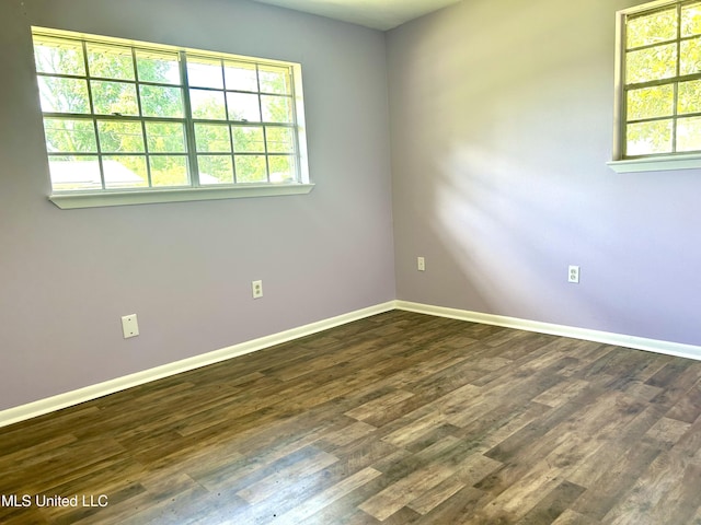 empty room featuring dark wood-style flooring and baseboards